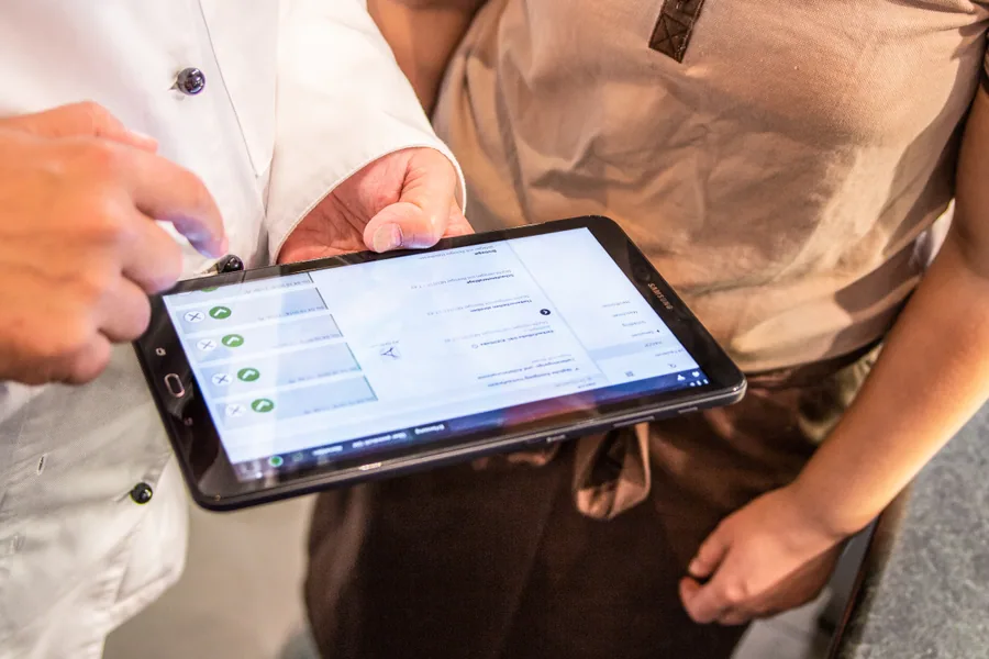 Heinz-Dieter Polfers und Mitarbeiterin betrachten gemeinsam das Tablet.